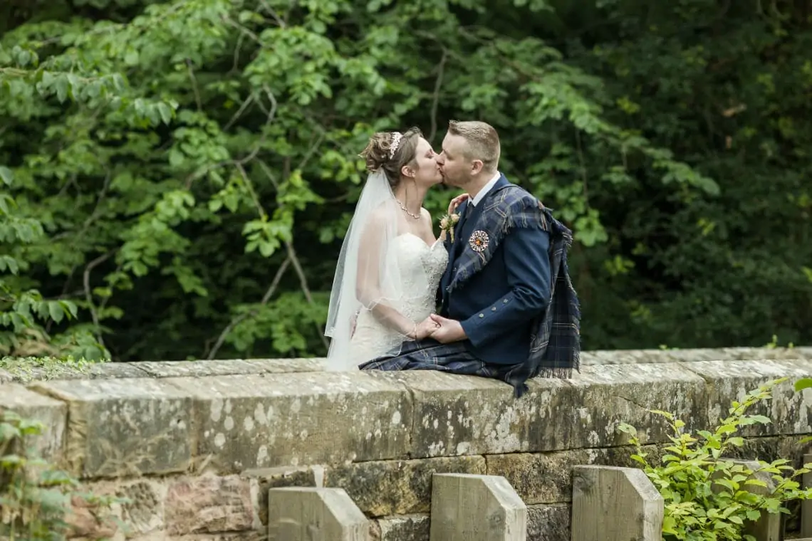 Bride and Groom kissing on a bridge.