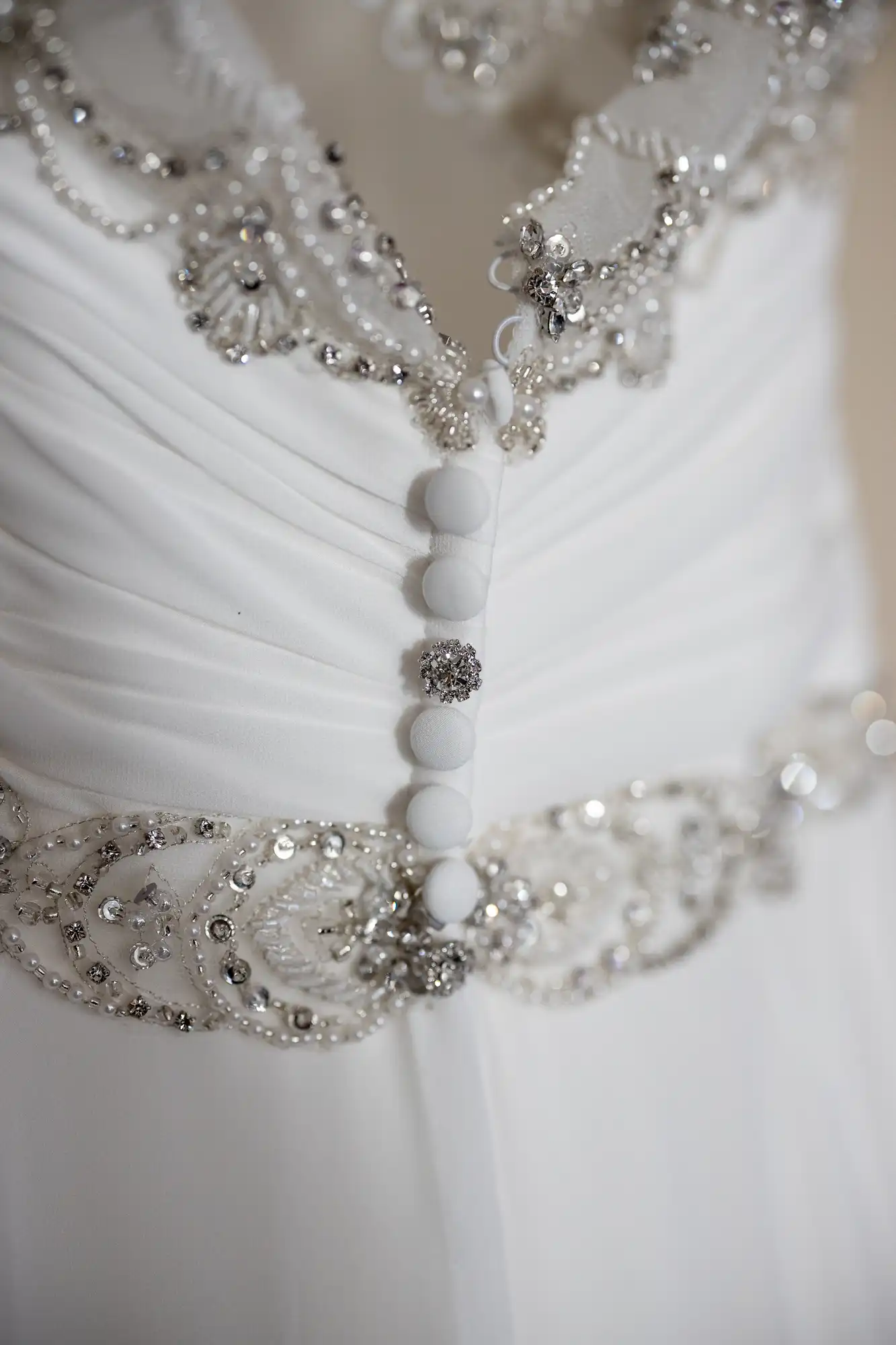 Close-up of a white wedding dress with intricate beaded embellishments and buttons running down the back.