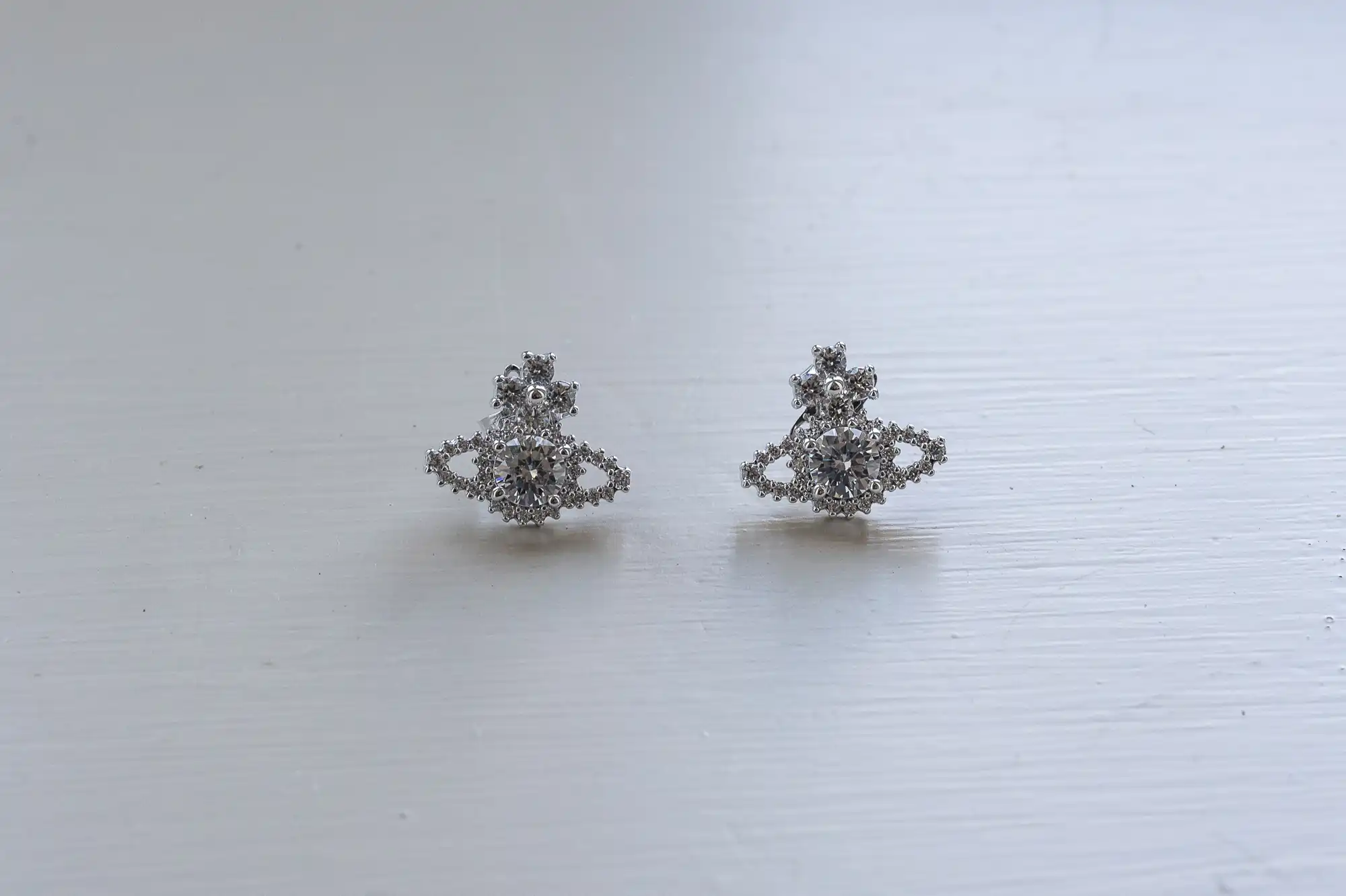 A pair of silver stud earrings with a detailed, intricate design on a white surface.