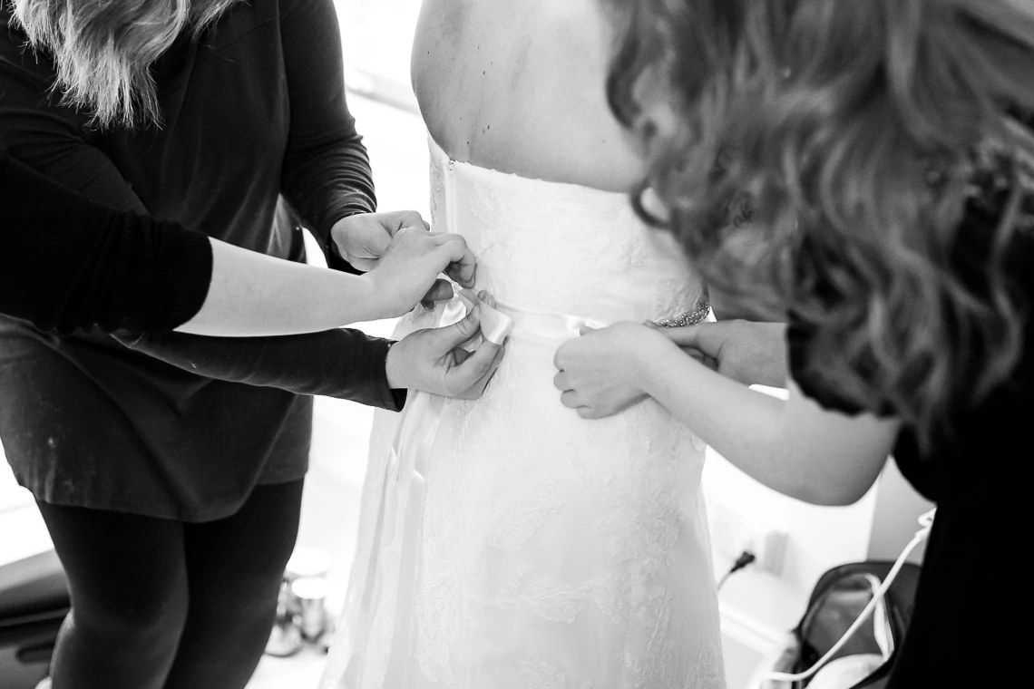 hands helping to tie wedding dress