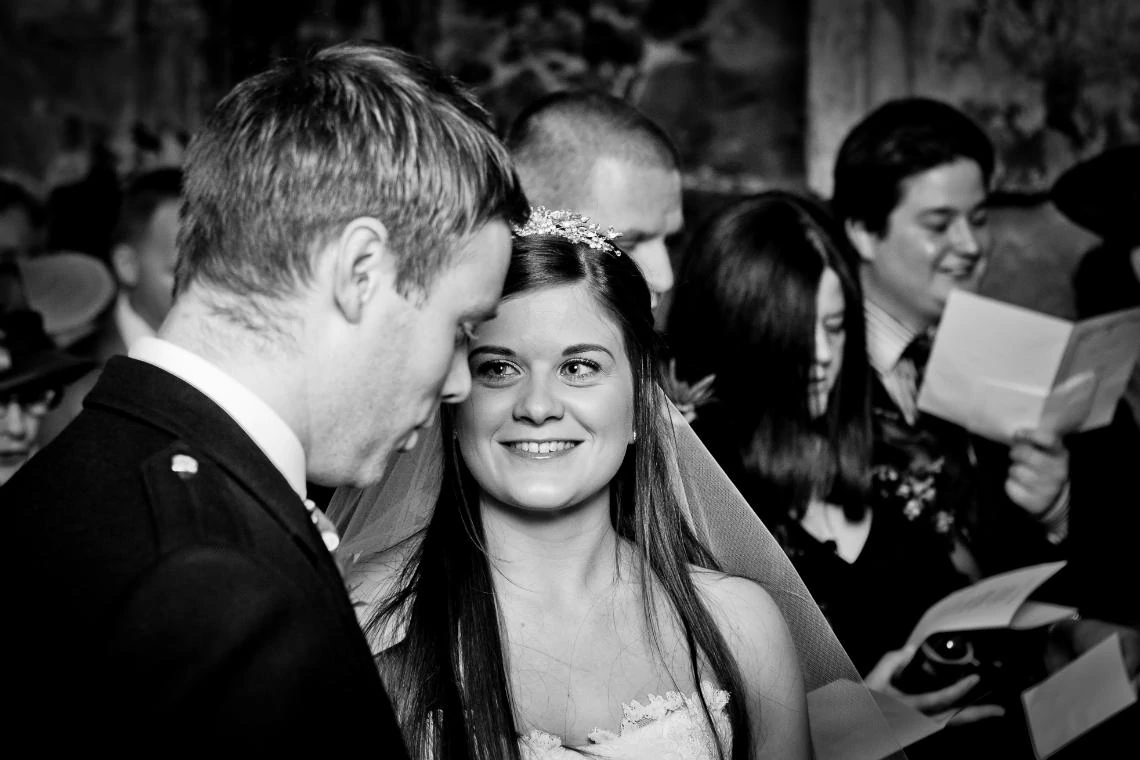 Bride smiles at her groom during hymn singing in the Auld Keep