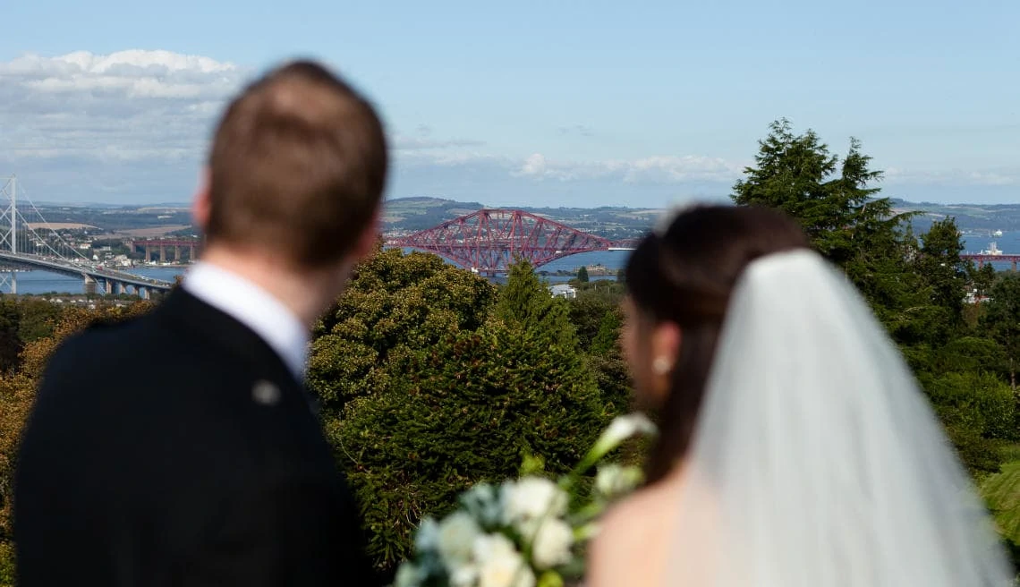 newlyweds looking towards the Forth bridges on the roof of the Auld Keep