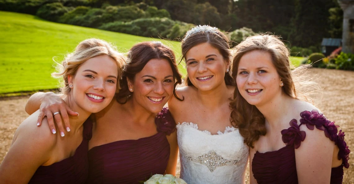 bride and bridesmaids group hug at the front of the castle