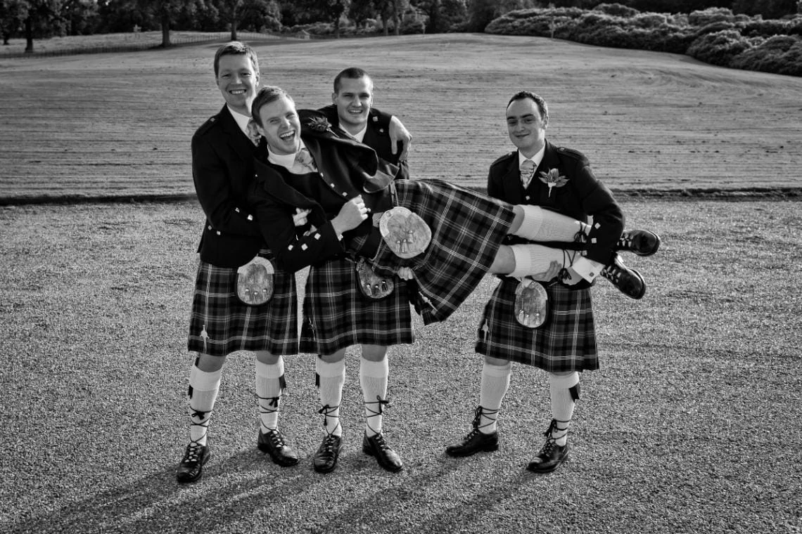 groomsmen holding the groom at the front of the castle