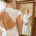 beautiful bride wearing a white dress looking into a full-length mirror in the Winter bedroom