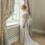 full length profile portrait of bride looking out of the window in the Winter bedroom