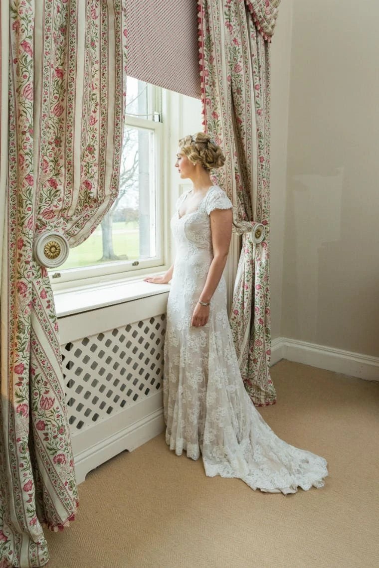 full length profile portrait of bride looking out of the window in the Winter bedroom