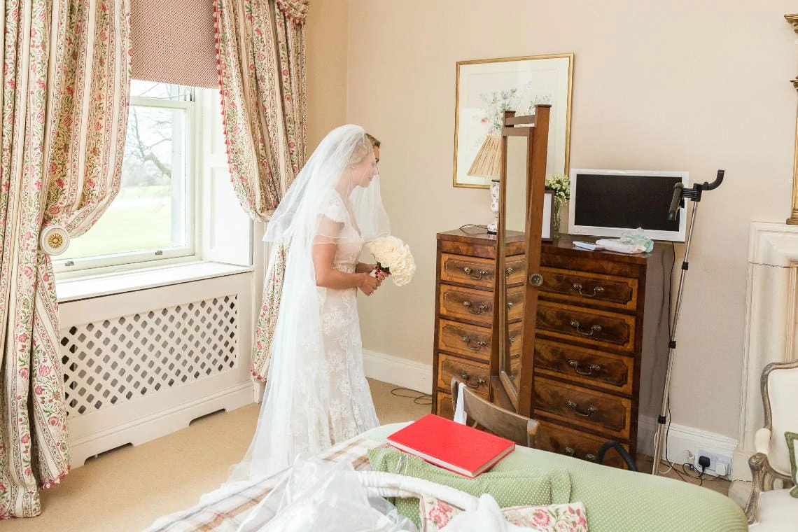 bride holding her bouquet and one final look in the mirror in the Winter bedroom before departing for the Auld Keep