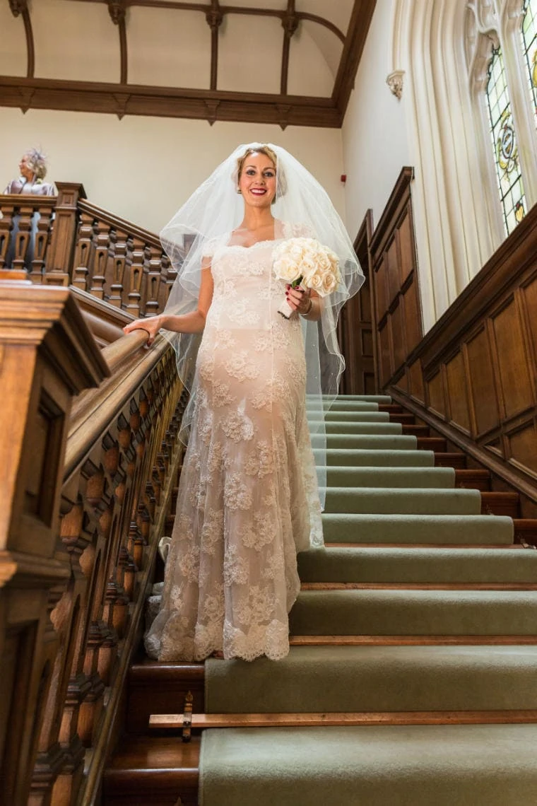 bride smiles at the camera as she makes her way down the staircase into the Main Hall