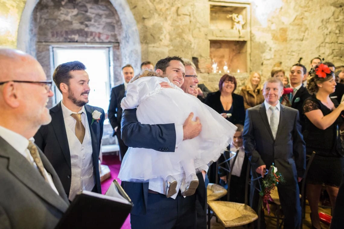 groom welcomes his flower girl daughter when she arrives in the Auld Keep