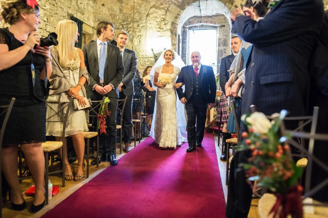 bride escorted by her father up the aisle in the Auld Keep