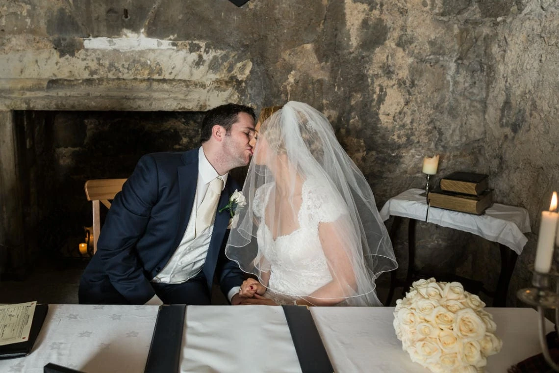newlyweds kiss after signing the marriage schedule in the Auld Keep annex