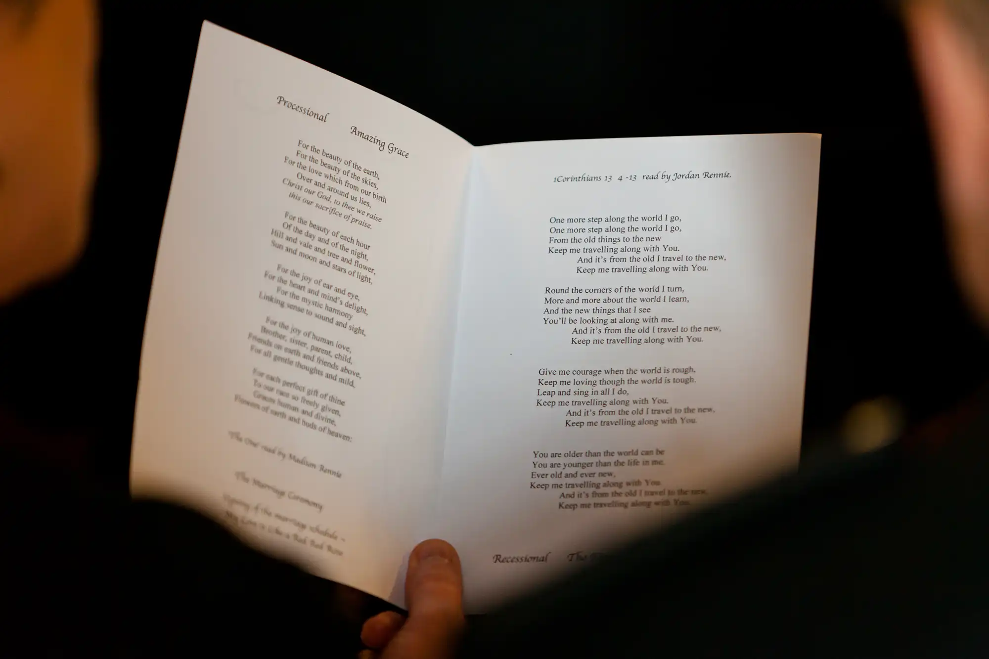 Two hands holding an open book with a visible poem titled "sometimes on a day full of wistful sprinkle.