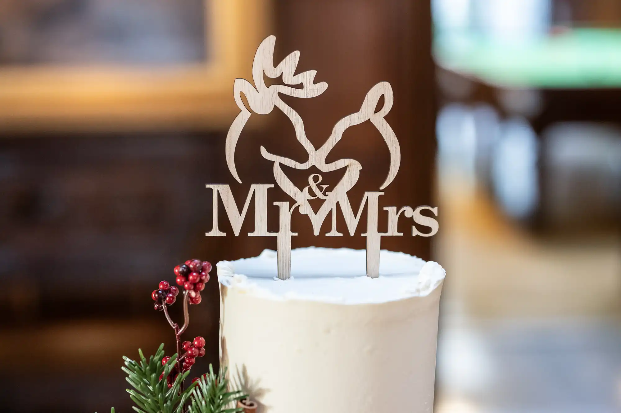 A white cake topped with a wooden decoration featuring two deer and the words "Mr & Mrs".