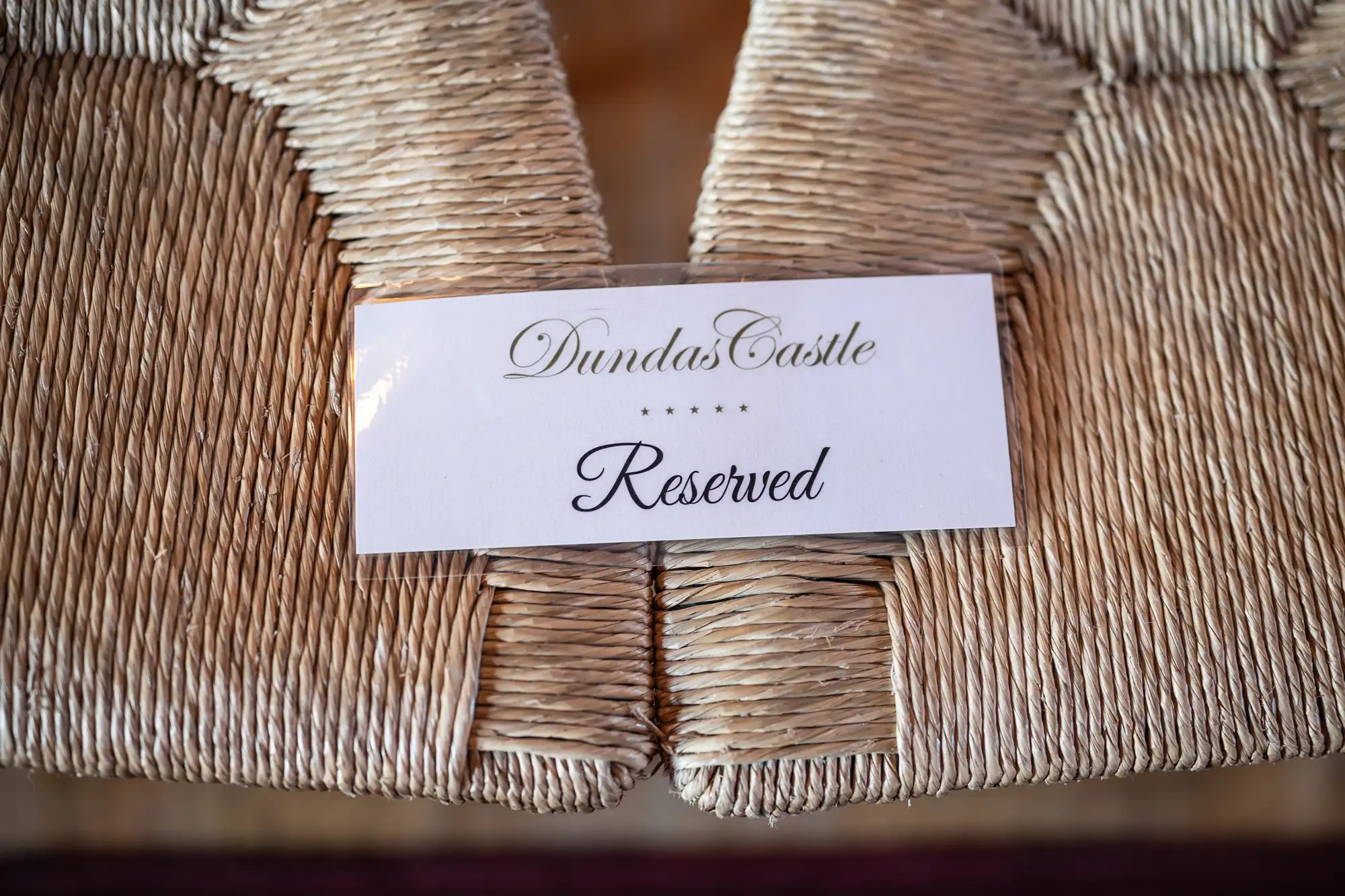 A white "Reserved" sign with "Dundas Castle" written above it is placed on a woven straw chair.