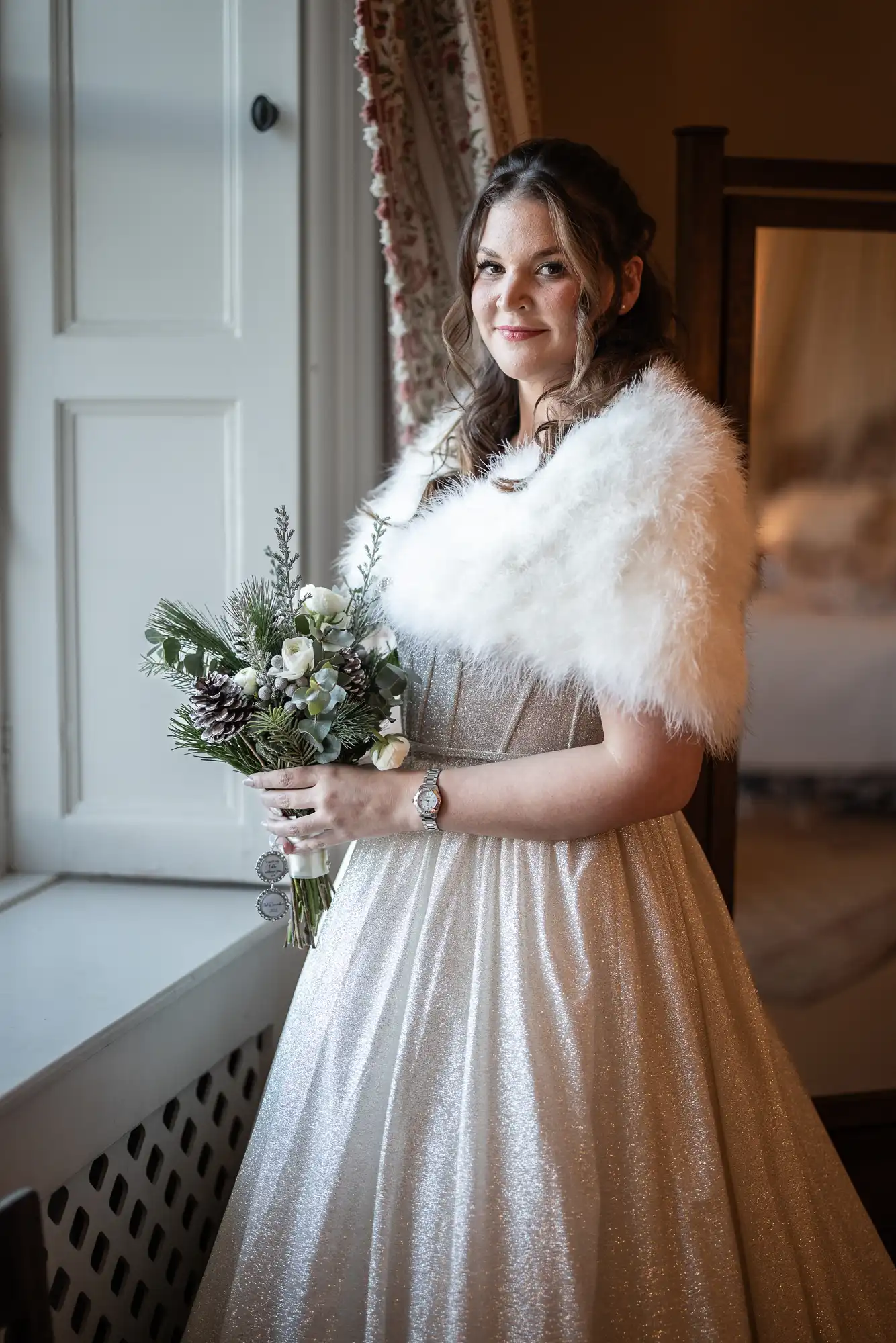 A woman wearing a white fur shawl and sparkly gown, holding a bouquet, stands by a window with a half-smile. The room features a large mirror and patterned curtains.