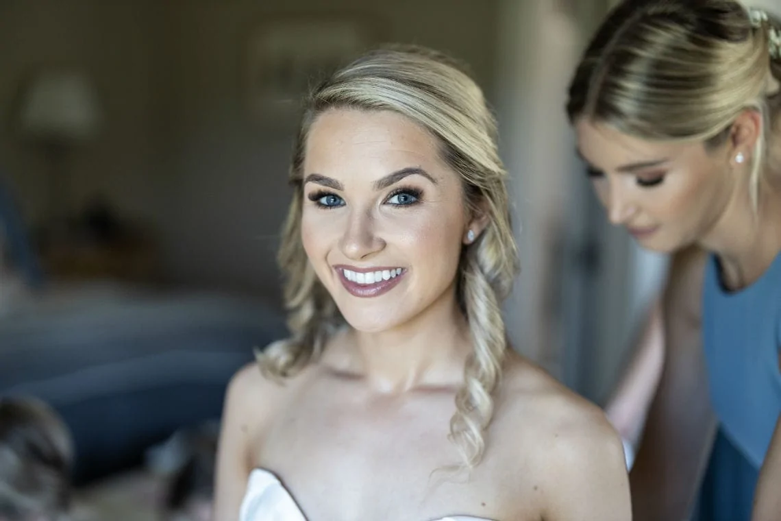smiling bride as her dress is buttoned up