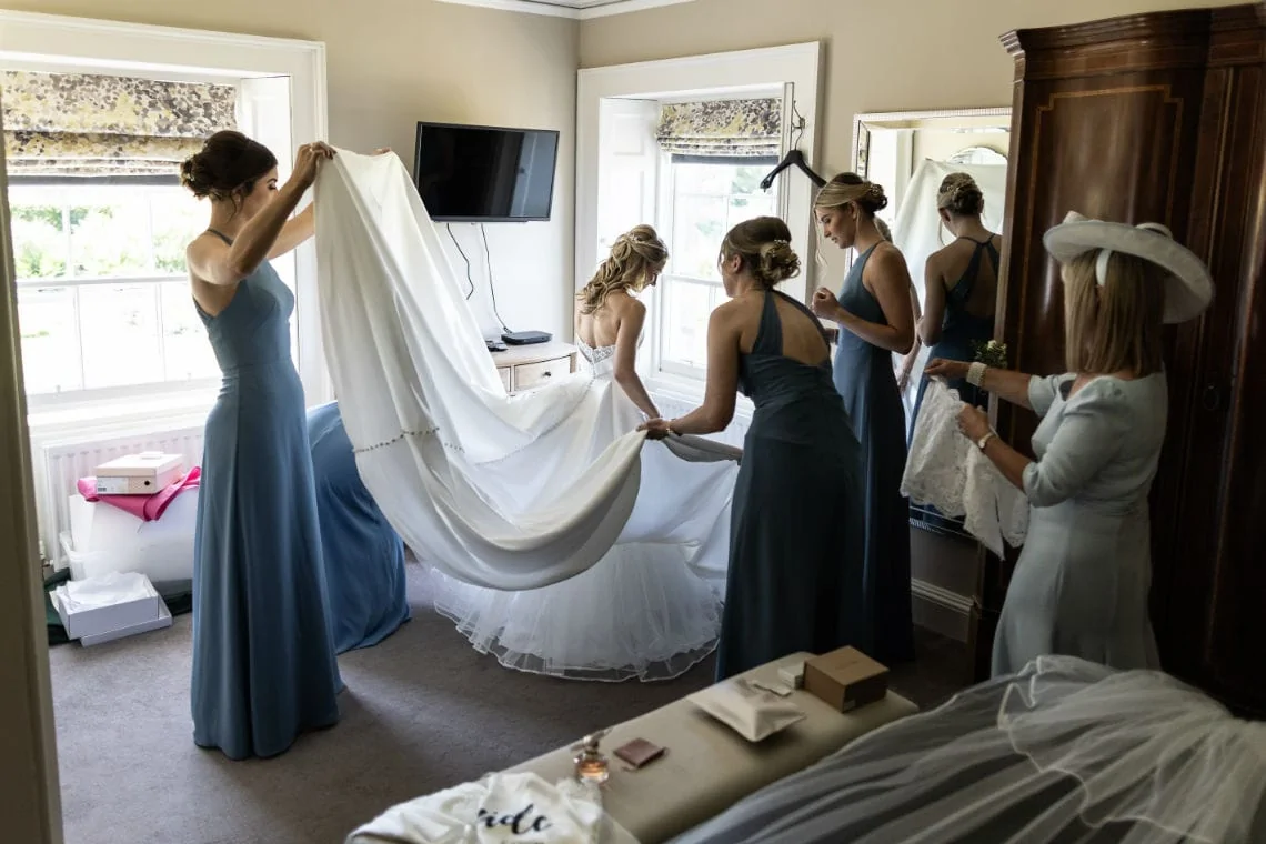 bridesmaids help bride into her dress in Sea View House