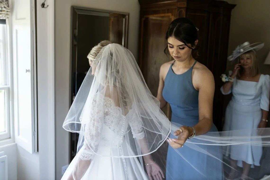 bridesmaid helps bride put on her veil