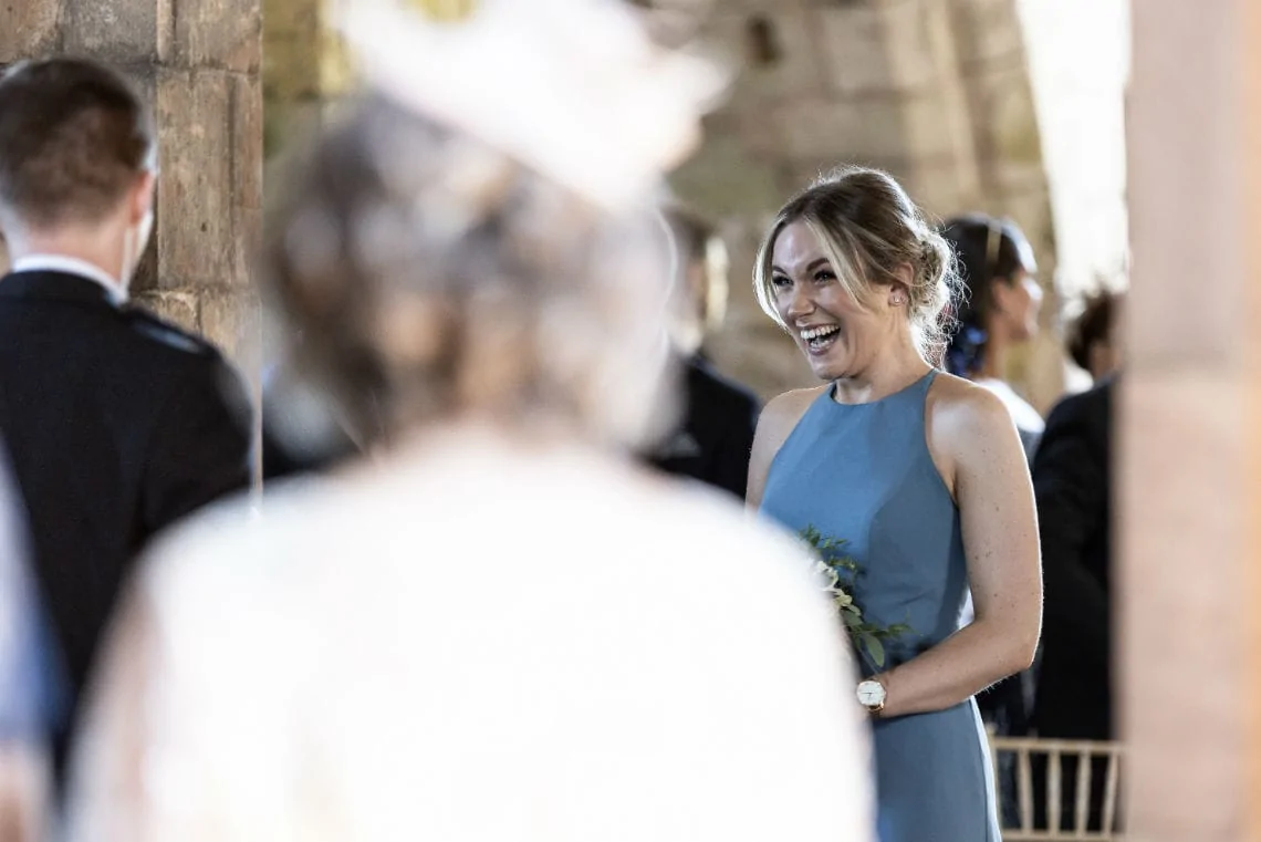 bridesmaid laughing and smiling as she walks up the aisle