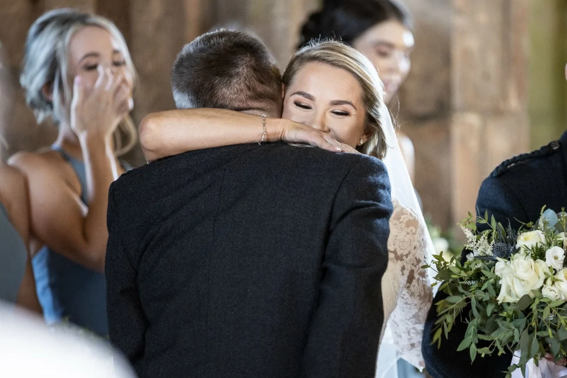 bride hugs her father after escorting her up the aisle