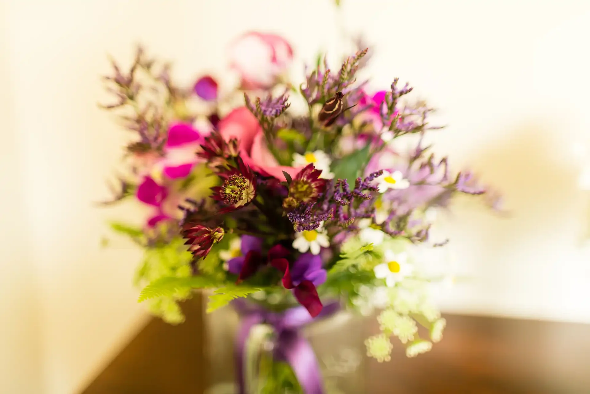A vibrant bouquet of flowers with purple and pink blossoms, set against a softly blurred background.