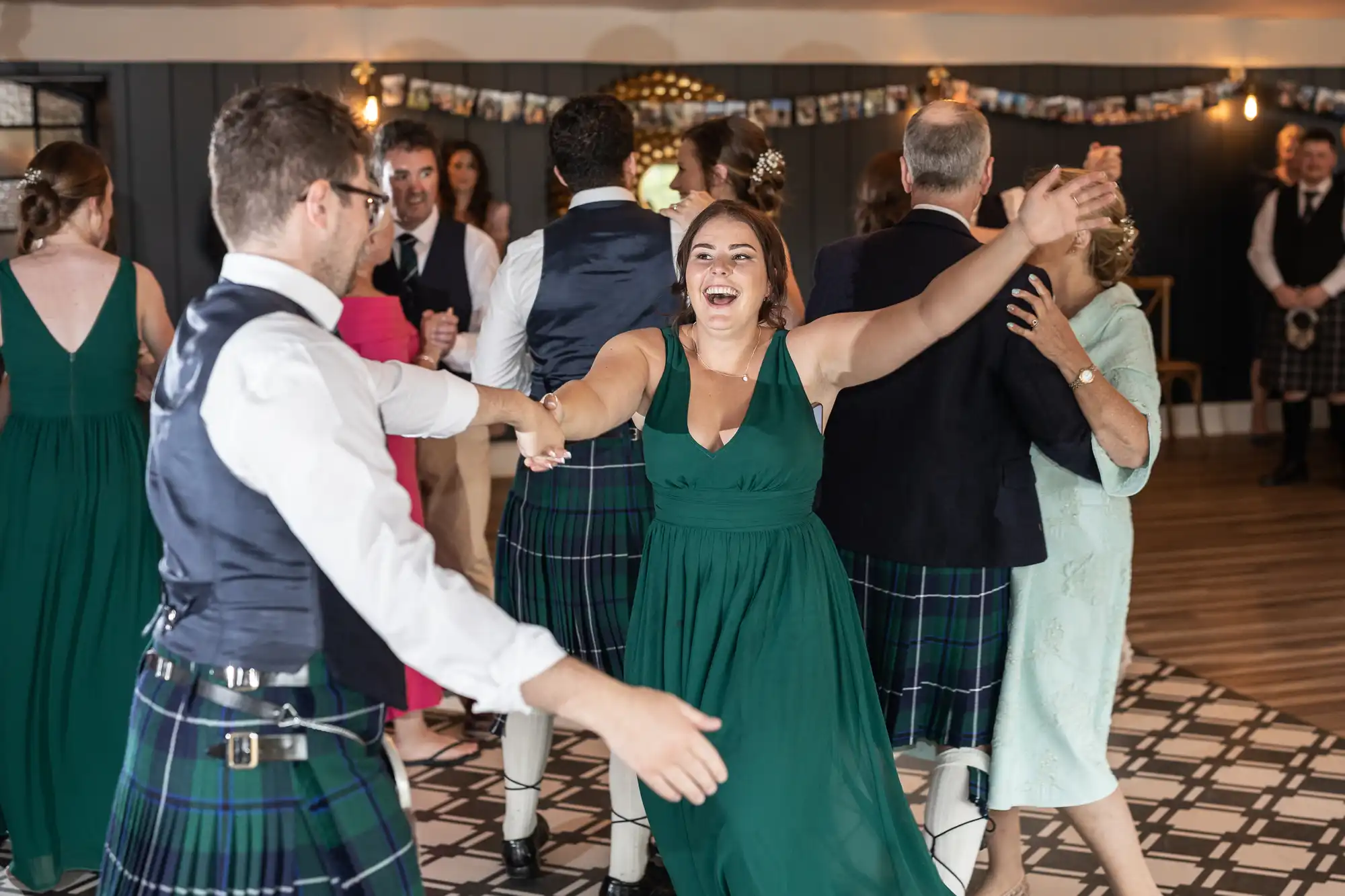 People in formal attire dancing energetically at an indoor event, with smiling faces and lively movements.