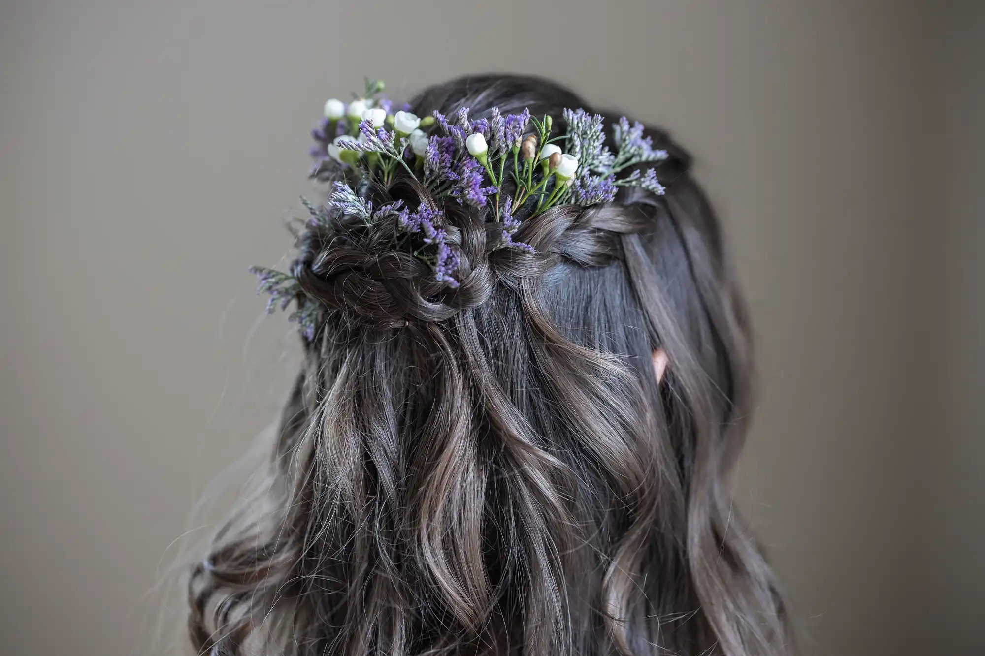 A woman's braided hairstyle with flowers and small white berries woven into it.