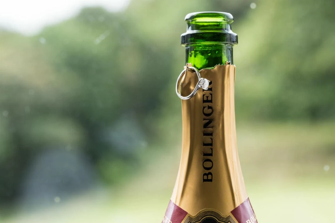 bride's engagement ring hanging from a bottle of Bollinger champagne