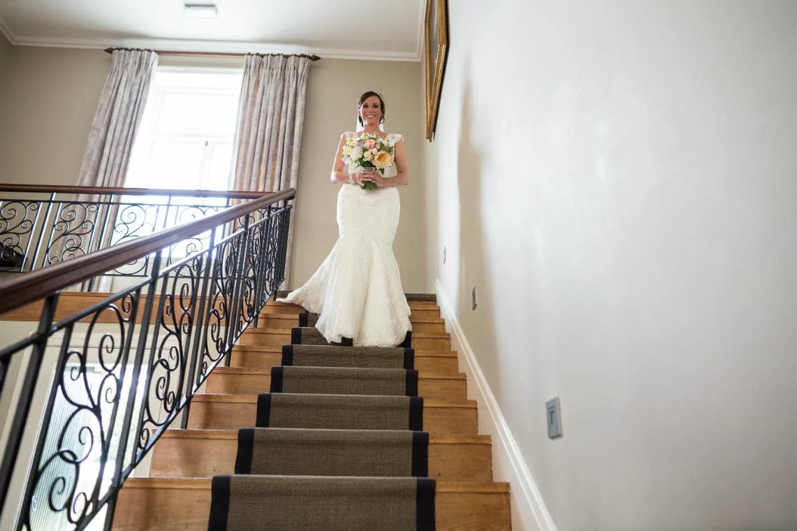 bride walks down the staircase of Dunglass House