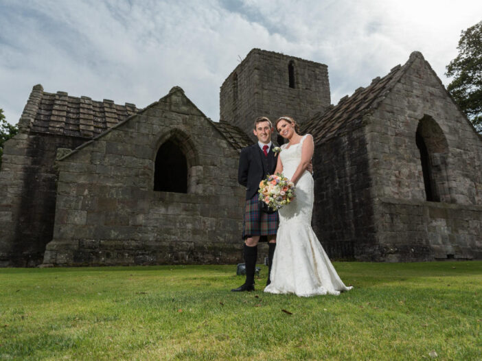 newlyweds standing in front of Dunglass Collegiate Church