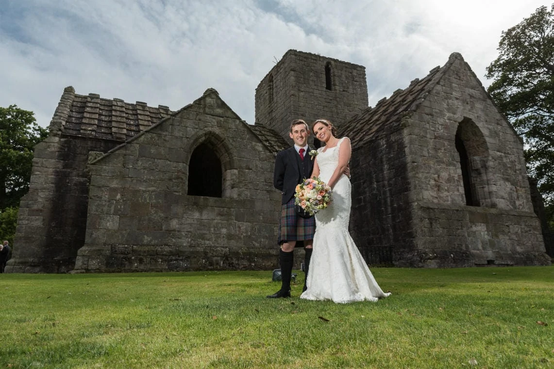 newlyweds standing in front of Dunglass Collegiate Church