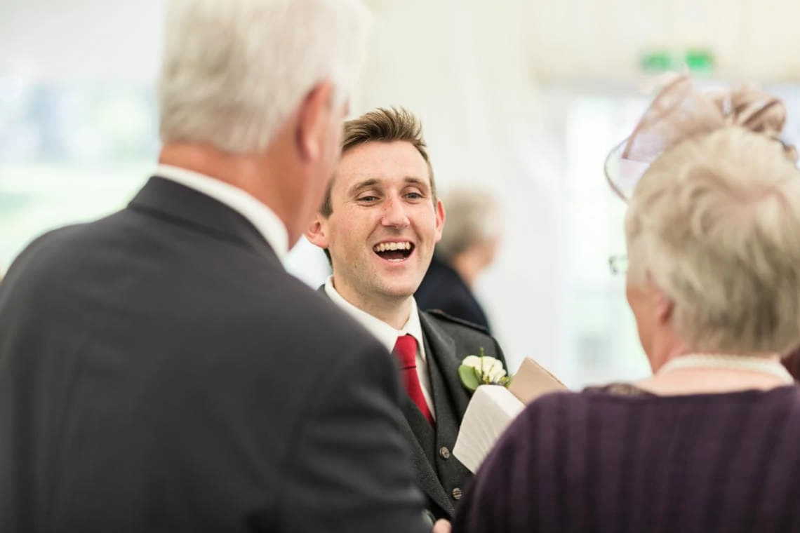 groom chats with guests in the marquee