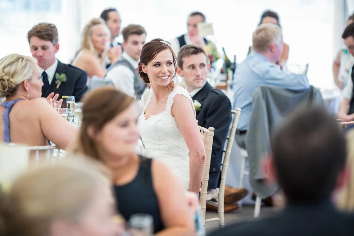 bride smiles as her father delivers his speech