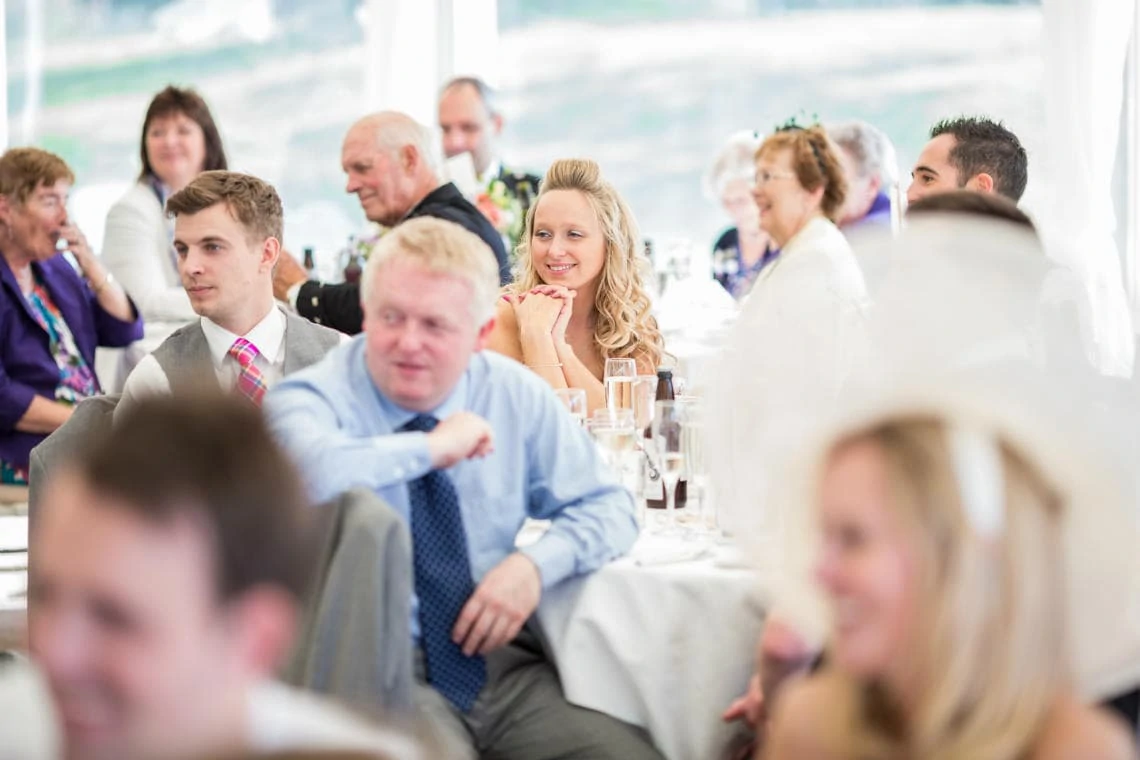 female guest smiling as she listens to father of the bride speech