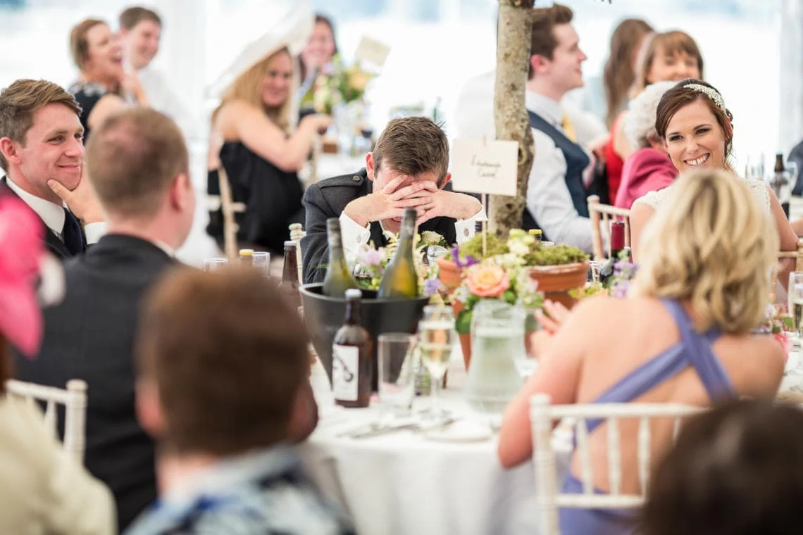 groom holds his head in his hands during the best man speech