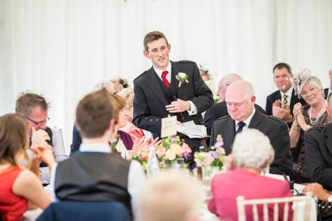 the groom delivers his speech in the marquee