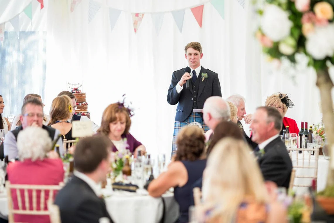 best man delivers his speech view from the rear of the marquee