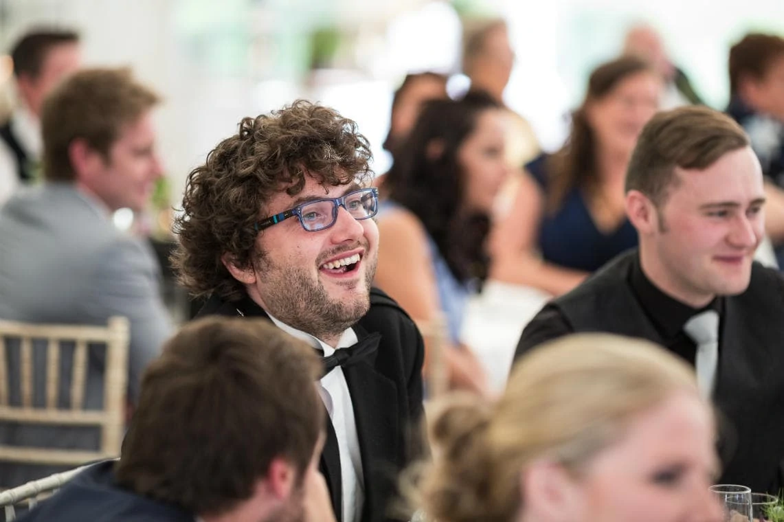 male guest laughing during the best man's speech