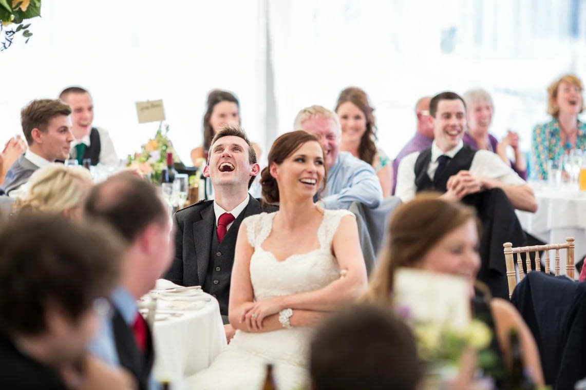 bride and groom laughing during the best man's speech