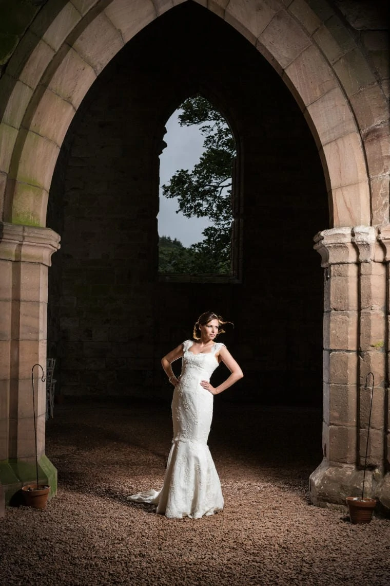 bride standing with her hands on her hips in Dunglass Church in the evening