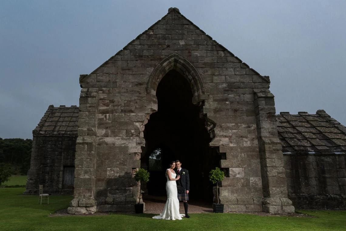 bride and groom standing on the lawn outside the church in the evening