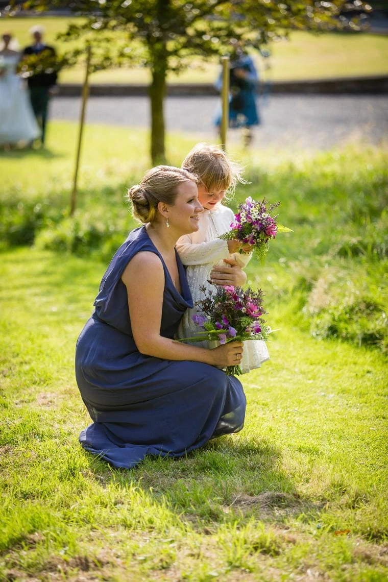 bridesmaid and flower girl holding their flowers on the way to Dunglass Church