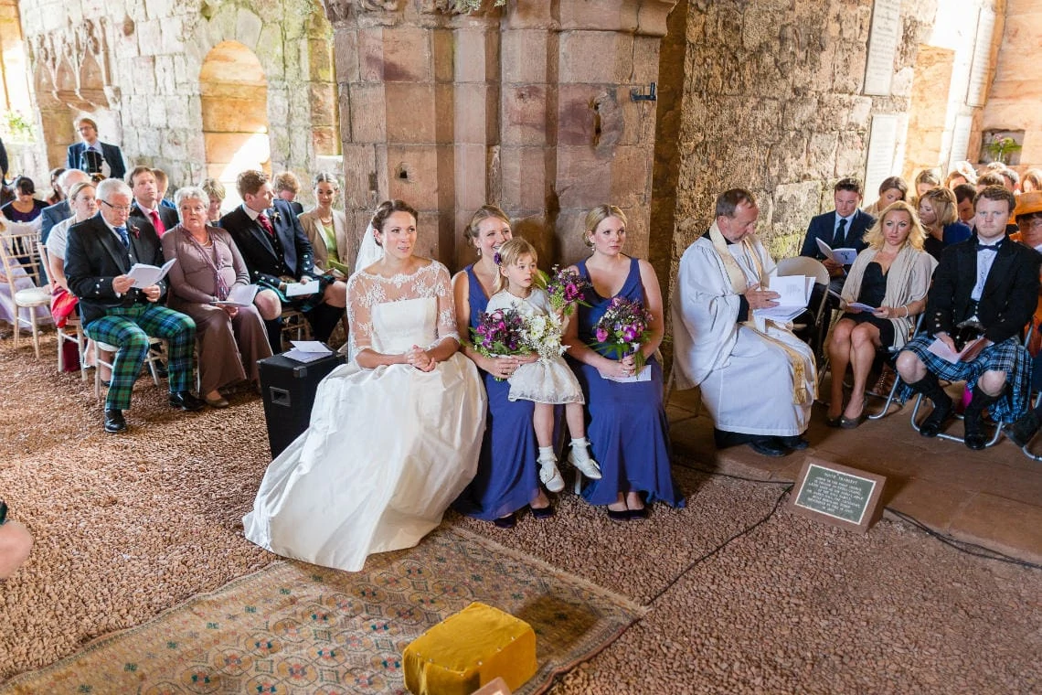 bride and bridesmaids seated as they listen to the readings