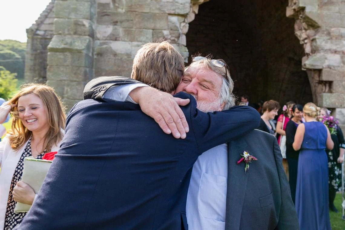 groom is congratulated by his father outside the church