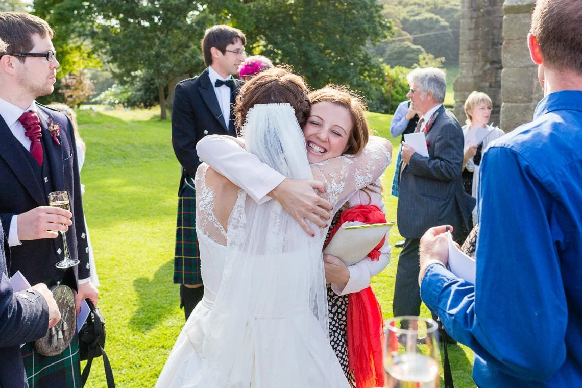 a female guests hugs and congratulates the bride outside the church