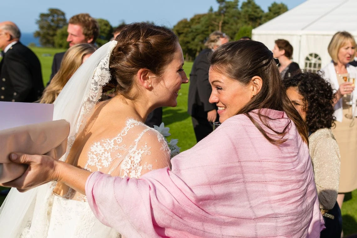 a female guest smiles as she congratulates the bride