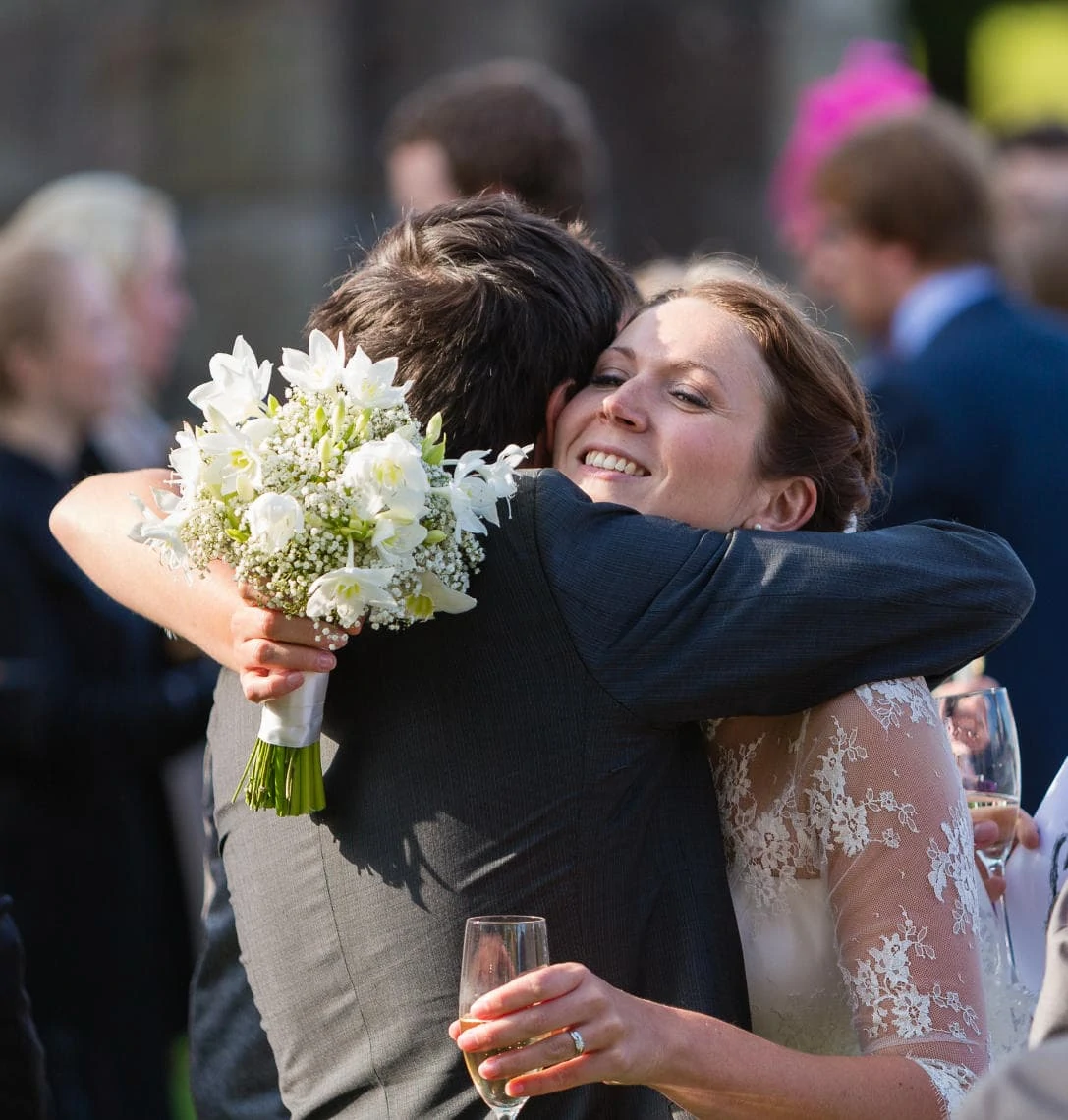a male guest hugs the bride during the champagne reception