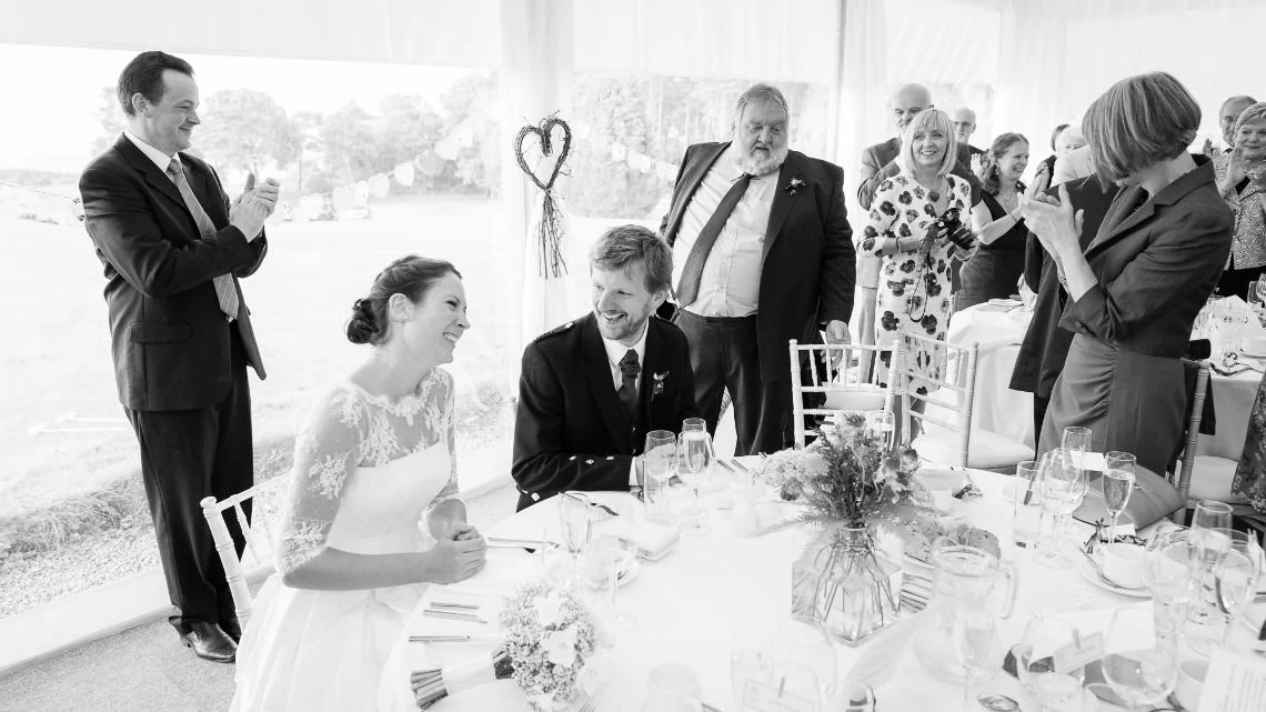 newlyweds smiling as they take their seats at the top table