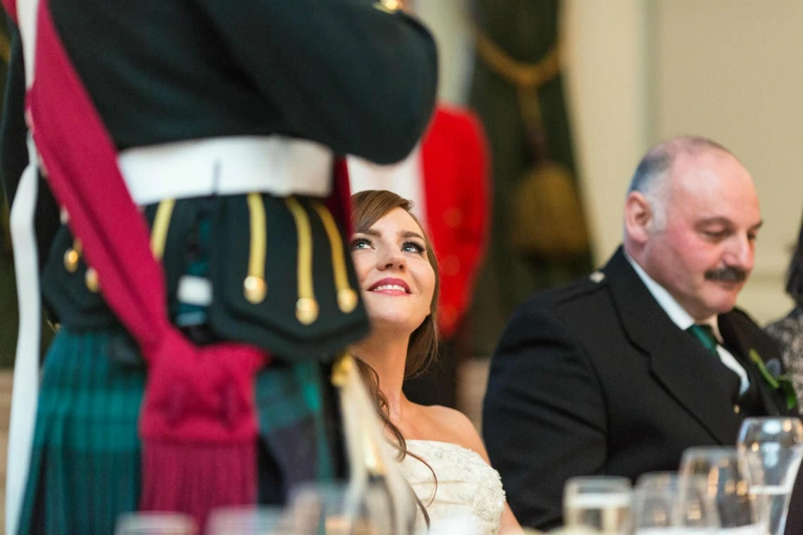 bride smiles at her husband during his speech
